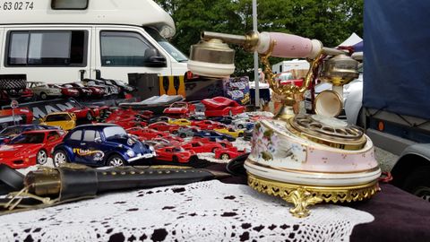 Ein Antiquitätenmarkt mit einem alten Telefon und verschiedenen Spielzeugautos im Hintergrund. Der Tisch ist mit einer Häkeldecke dekoriert.