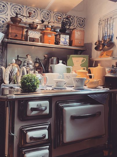 A nostalgic kitchen with a classic stove and fine china. Various kitchen appliances and decorations hang above the countertop.