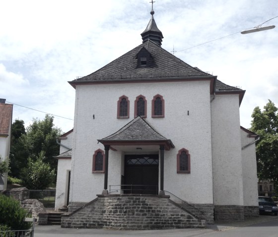 &Eacute;glise blanche &agrave; Flie&szlig;em avec un toit rouge et un clocher, entour&eacute;e d'arbres et de maisons voisines. Le ciel est l&eacute;g&egrave;rement nuageux., &copy; TI Bitburger Land