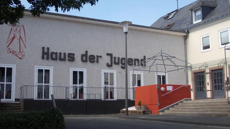 Ein modernes Gebäude mit der Aufschrift "Haus der Jugend". Es hat eine Zugangsrampe und große Fenster.