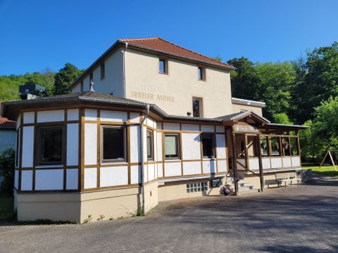 Ein charmantes Gebäude mit holzverkleidetem Erdgeschoss und einem hellen Obergeschoss. Umgeben von Grünflächen, strahlt es eine einladende Atmosphäre aus.