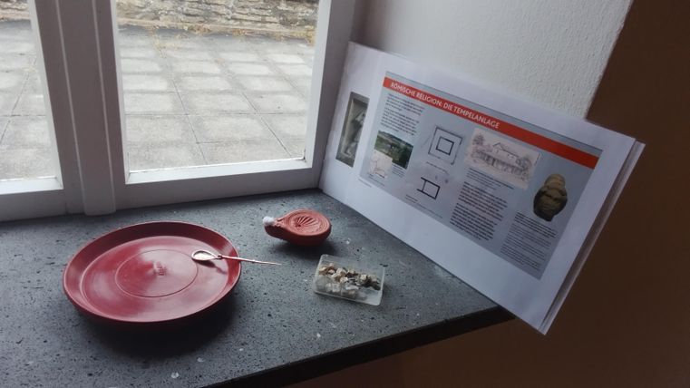 Une assiette rouge et un petit bol se trouvent sur un rebord de fenêtre. À côté se trouve une feuille d'information avec des explications textuelles.