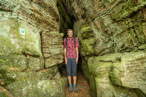 Person in karierter Hemd steht in enger Felsenschlucht.