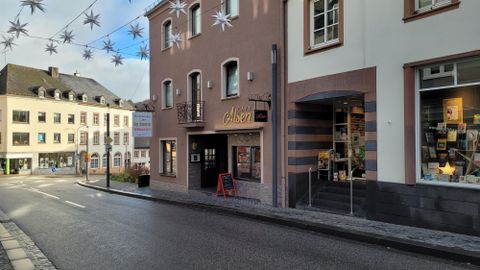 Une rue calme avec des magasins et un café. Des étoiles décoratives pendent au-dessus de la rue.