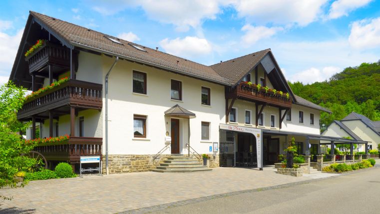 Ein hübsches Gebäude mit Balkonen, umgeben von Grün. Der Parkplatz vor dem Haus ist gut zugänglich.