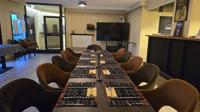 Een elegante eetruimte met een lange tafel en stoelen. De tafelkleden zijn stijlvol gedecoreerd en de ruimte is goed verlicht.