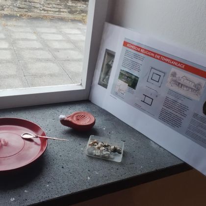 Une assiette rouge et un petit bol se trouvent sur un rebord de fenêtre. À côté se trouve une feuille d'information avec des explications textuelles.