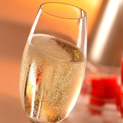 A glass of sparkling drink stands in front of a blurred background. It is elegant and inviting, ideal for festive occasions.