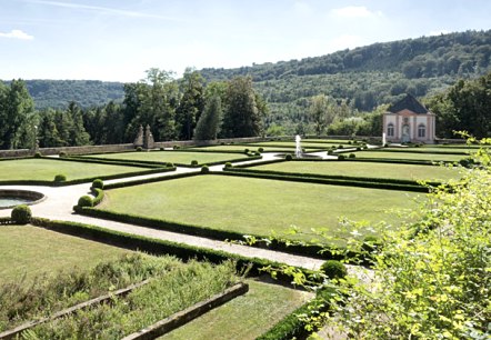 Jardin &agrave; la fran&ccedil;aise avec des haies et des pelouses sym&eacute;triques, au fond un petit b&acirc;timent et des collines bois&eacute;es sous un ciel bleu., &copy; V. Teuschler
