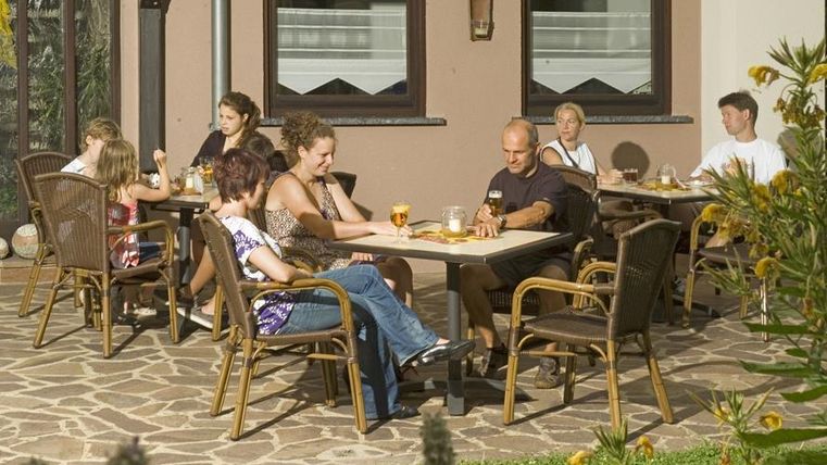 A group of people is sitting relaxed on a terrace. They are enjoying drinks and snacks in a friendly atmosphere.