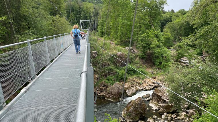 A woman crosses the suspension bridge over the Irreler Waterfalls.
