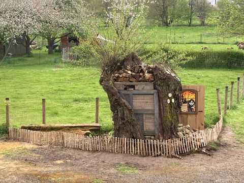 Een creatief Boomhut met houtstapel en een kleine ingang. Het staat op een groene wei, omringd door een houten hek.